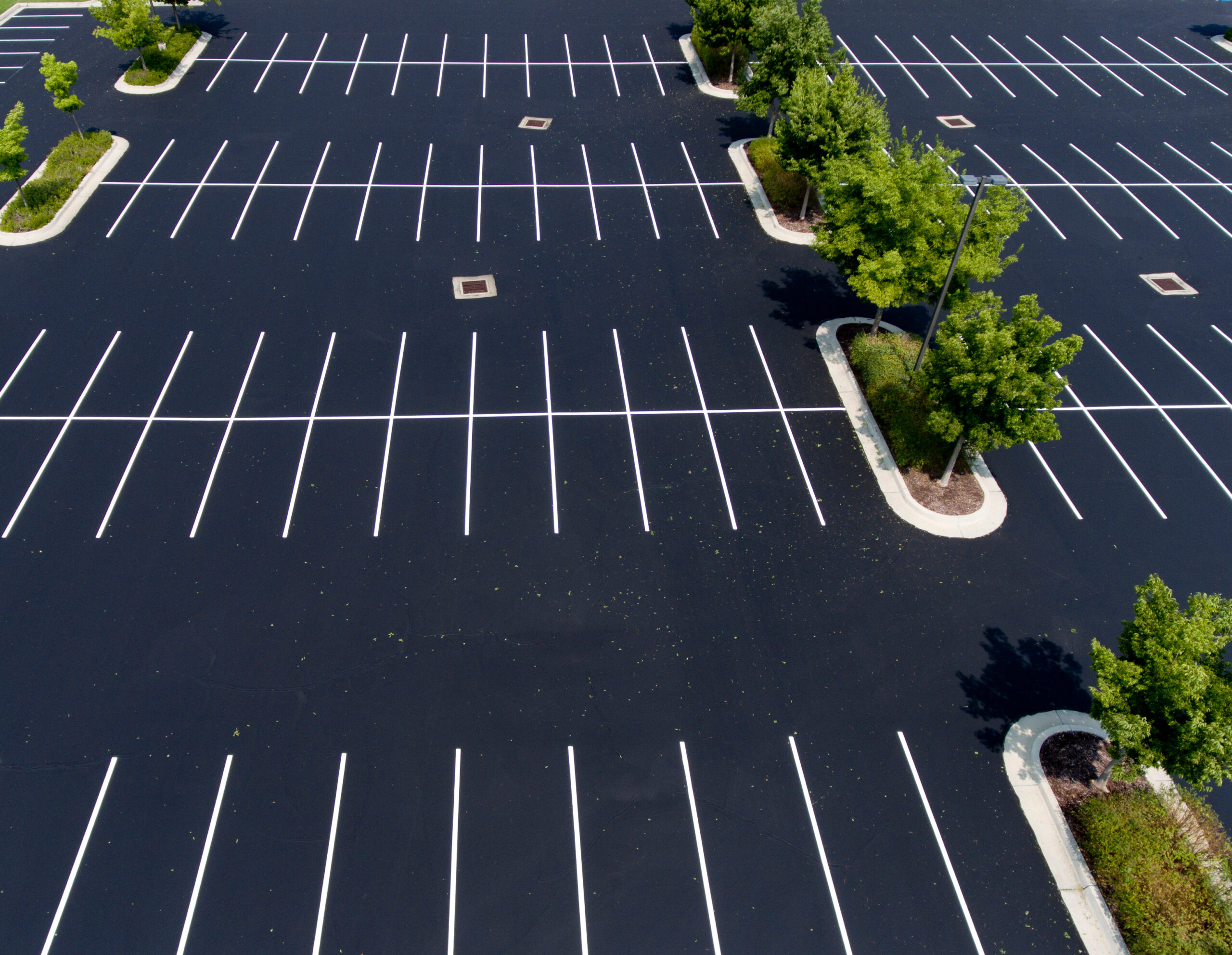 parking lot,asphalt,island,trees,stalls,parking stalls,paint,green